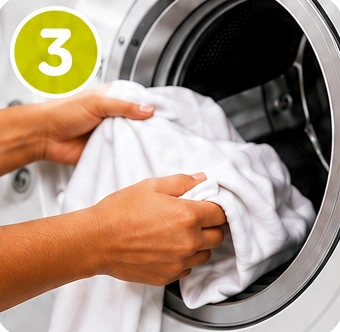Mãos colocando a roupa na máquina de lavar